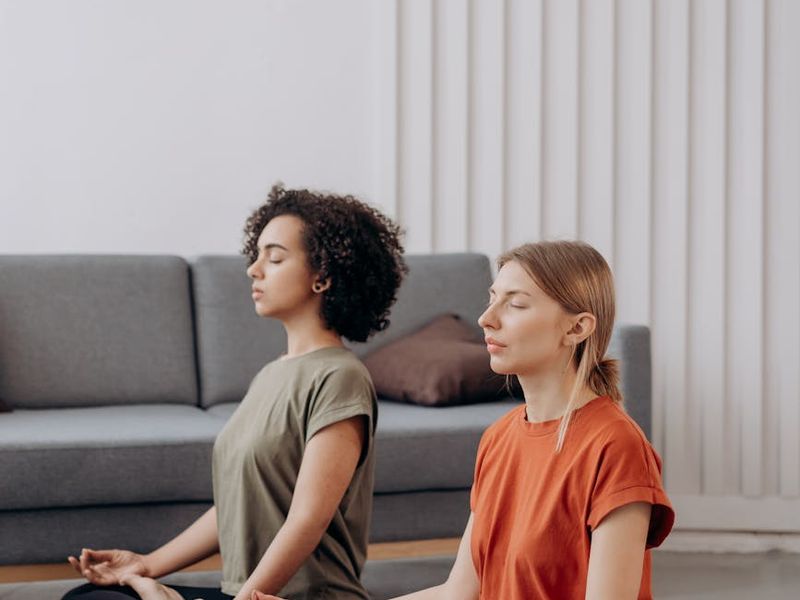 Person in a calm yoga pose in a minimalist dark room.